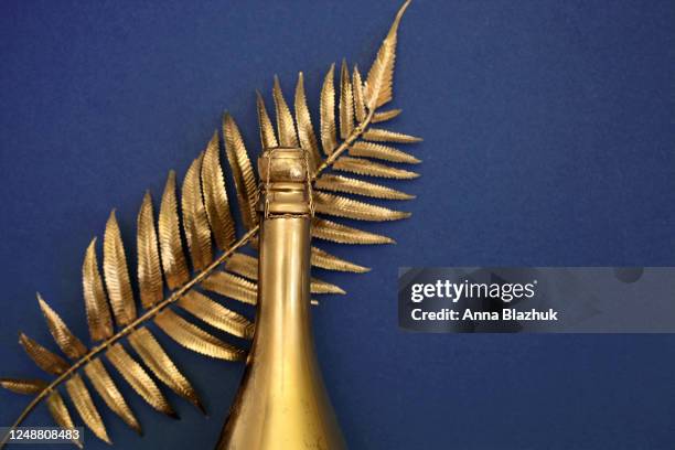 dark blue background with golden champagne bottle and golden fern leaf. copy space for text. - champagne or photos et images de collection