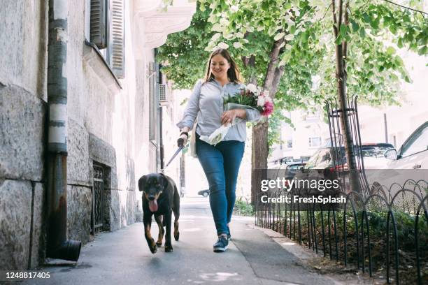 gelukkige plus grootte vrouw die haar hond op de straat loopt - happy lady walking dog stockfoto's en -beelden