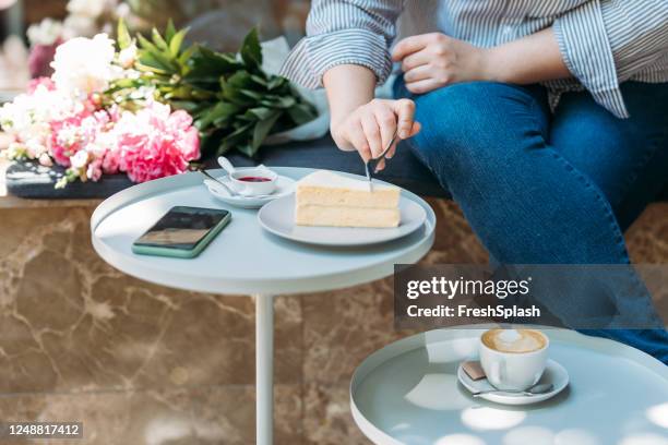 donna irriconoscibile che mangia una fetta di torta e beve caffè in un caffè all'aperto - jeans cake foto e immagini stock