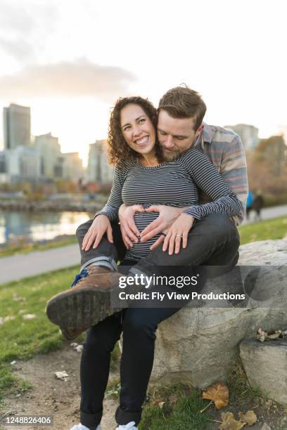 de zwangere vrouw die als dwaze echtgenoot lacht maakt hartvorm met zijn handen op haar groeiende buik - 2 5 maanden stockfoto's en -beelden