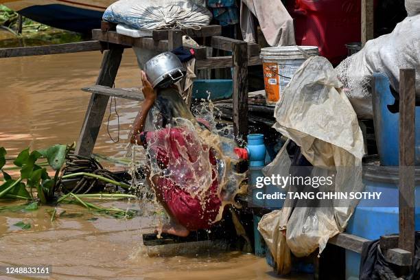 This photo taken on March 13, 2023 shows a girl taking a bath near floating toilets in Chong Prolay village on Tonle Sap lake in Siem Reap province....