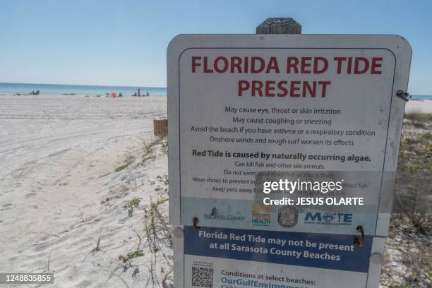 Sign warning of the red tide risk is displayed at Lido Key Beach in Sarasota, Florida, on March 15, 2023. - With its brilliant sun, white sand and...