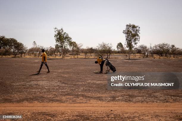 Golf player walks next to his caddy at Ouagadougou's Golf Club, on February 25, 2023. - When Burkina Faso makes the headlines these days, it's...