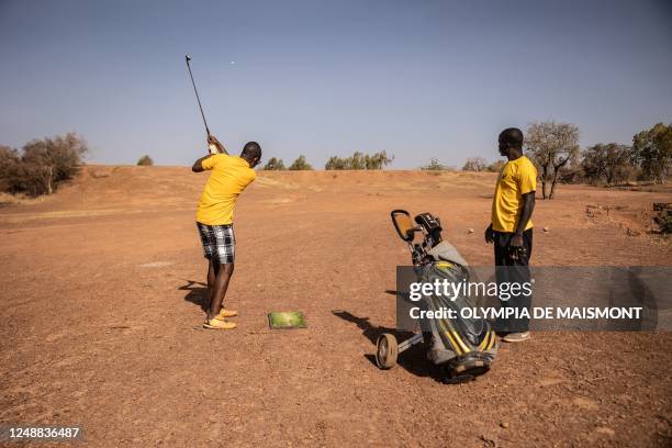 Man plays golf next to a caddy at Ouagadougou's Golf Club, on February 25, 2023. - When Burkina Faso makes the headlines these days, it's usually...