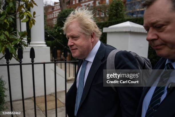 Former British prime minister Boris Johnson is escorted by a police officer as he leaves his home on March 20, 2023 in London, England. The former...