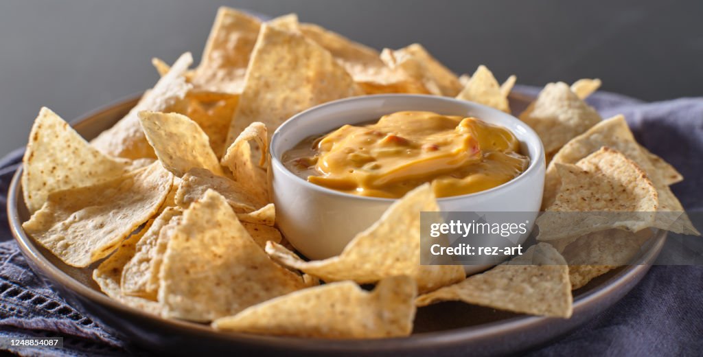 Mexican hot queso cheese dip with corn tortilla chips on plate