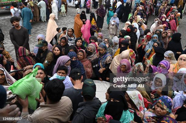 People stand in queues to receive the free bags of flour from a delivery truck at a distribution point ahead of the Muslim holy fasting month of...