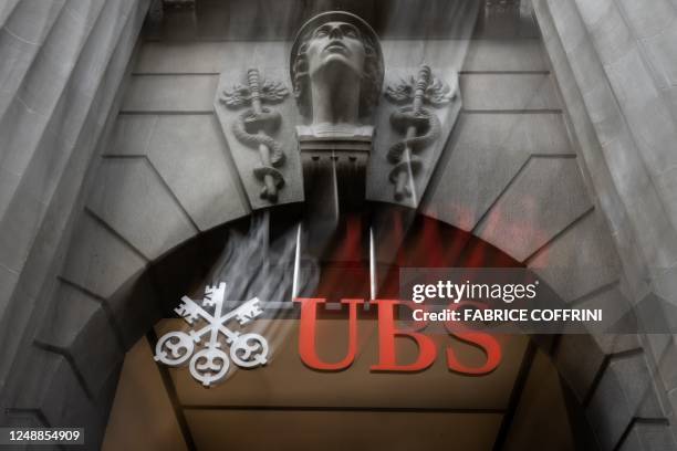 This photograph taken on March 20, 2023 shows the Swiss giant banking UBS' logo at the entrance of their headquarters in Zurich. - UBS share price...