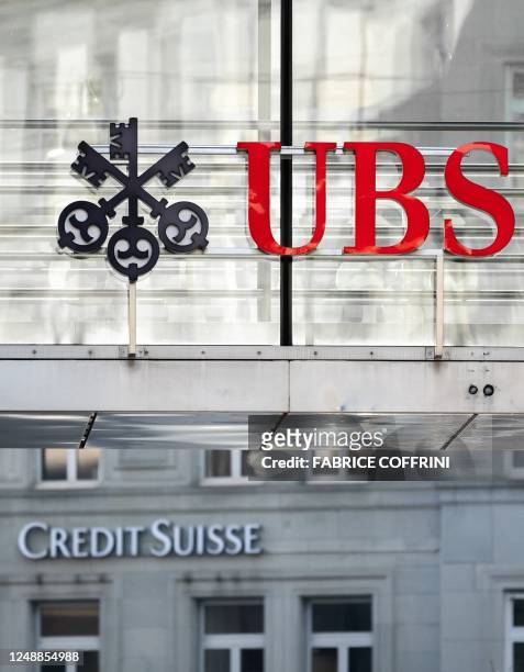 Sign and logo of Credit Suisse bank is seen beneath a sign of Swiss giant banking UBS in Zurich on March 20, 2023. - Shares in European banks sank on...