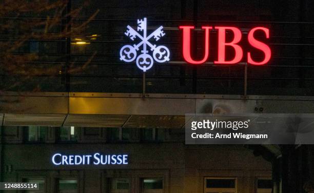 Traffic sign is seen in front of the logos of Swiss banks Credit Suisse and UBS the day after its shares dropped approximately 30% on March 16, 2023...