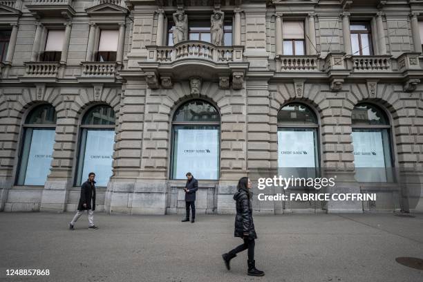 People are walking past the headquarters of Credit Suisse bank in Zurich on March 20, 2023. - UBS agreed to take over Credit Suisse for $3 billion...