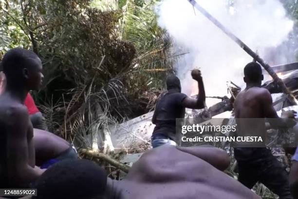 This frame grab taken from AFPTV shows locals trying to put out a fire burning parts of a military helicopter after crashing in Choco, northwestern...