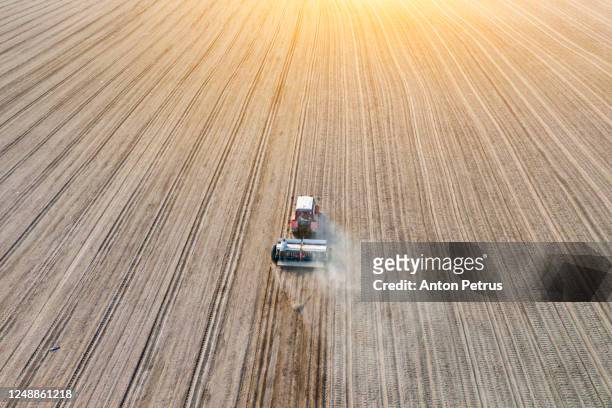 aerial view of tractor at sunset on the field - säen stock-fotos und bilder