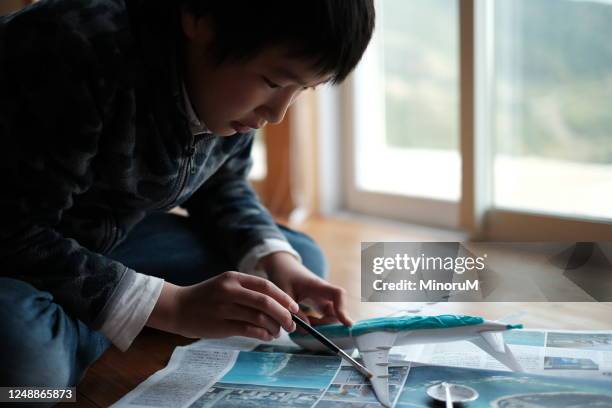 boy assembling a plastic model of airplane - model airplane stock pictures, royalty-free photos & images