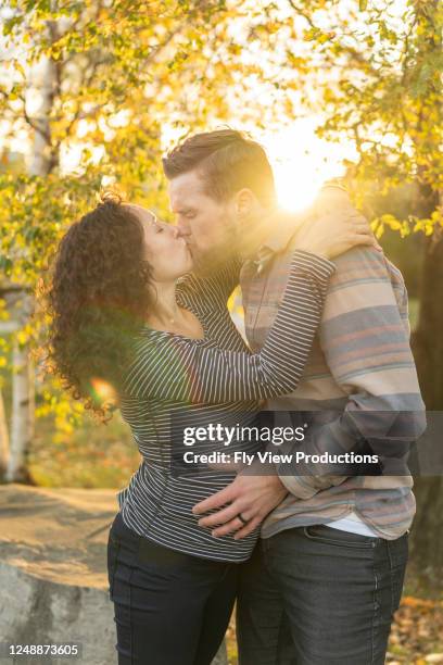 de zwangere vrouw in haar tweede trimester kust echtgenoot aangezien hij liefkozend haar groeiende buik houdt - 2 5 maanden stockfoto's en -beelden