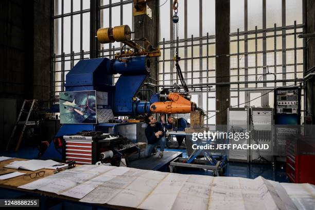 Employees of the French aeronautics, space and defense research lab examine a mechanical arm at Modane-Avrieux ONERA center in Modane, on March 17,...