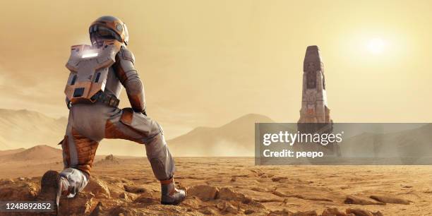 astronaut on mars kneeling looking at space rocket in distance - mars atmosphere stock pictures, royalty-free photos & images