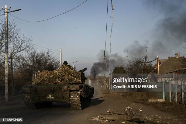 Ukrainian T64 tank moves towards Bakhmut in the town of Chasiv Yar as smoke rises from the direction of Bakhmut on March 20, 2023. - The head of...