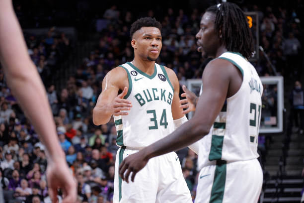 Giannis Antetokounmpo of the Milwaukee Bucks high fives teammate Jrue Holiday during the game against the Sacramento Kings on March 13, 2023 at...