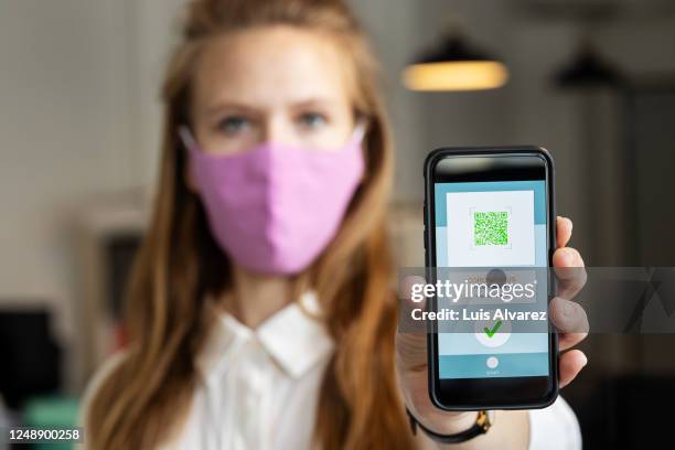 businesswoman showing corona virus tracking app on her phone - contract tracing stock pictures, royalty-free photos & images