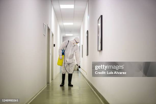 sanitation worker disinfecting office hallway - overall stockfoto's en -beelden