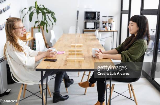 women at office cafeteria with a screen partition on table - coffee break office stock-fotos und bilder