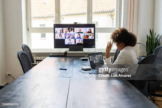 meeting over a video call in office post pandemic - zwaaien gebaren stockfoto's en -beelden