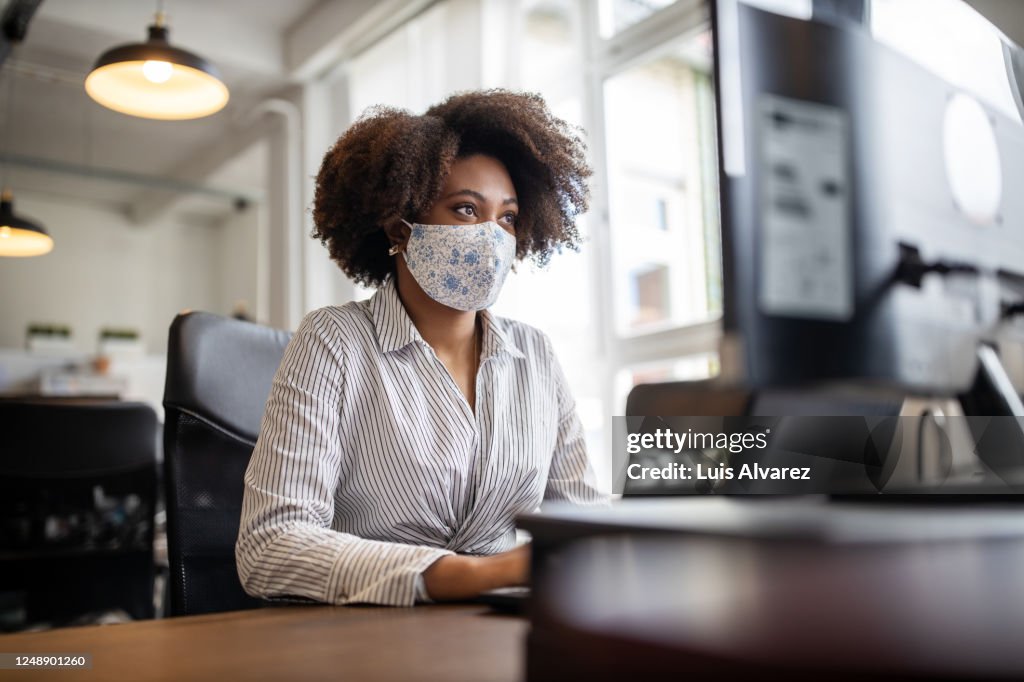 Businesswoman with face mask working at her desk