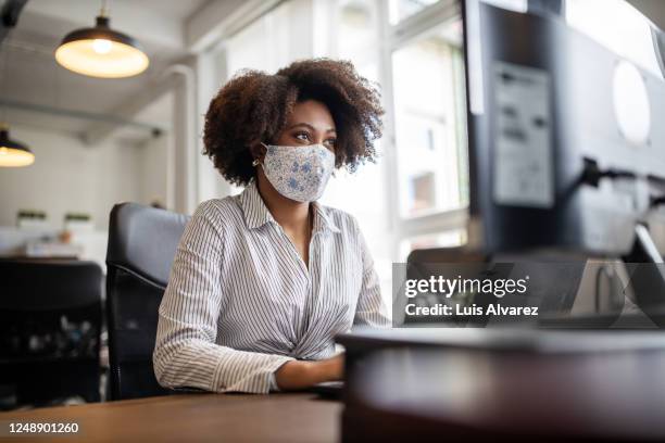 businesswoman with face mask working at her desk - health and safety covid stock pictures, royalty-free photos & images