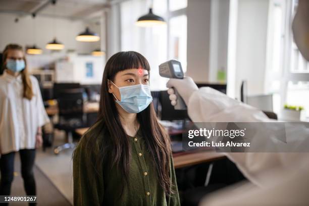 employees going through mandatory temperature checks in office - misurare la temperatura foto e immagini stock