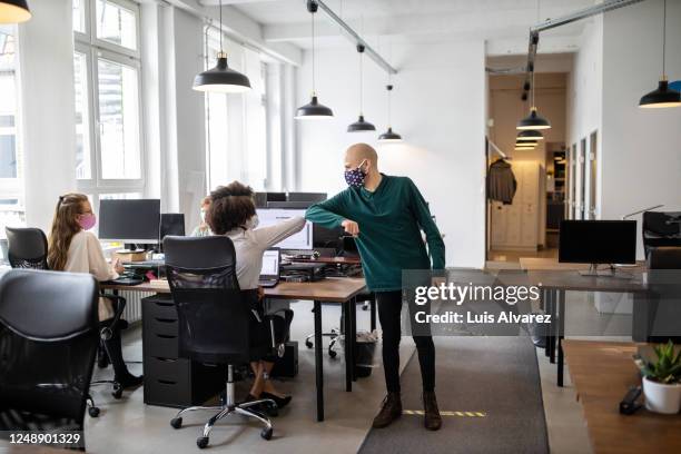 colleagues greeting with elbow bump in office - covid handshake stock pictures, royalty-free photos & images