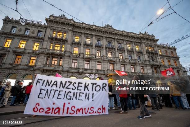 Protestors hold a sign reading "Expropriate the financial sector" as member of Young Socialists Switzerland party stage a demonstration in front of...