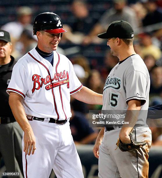 Chipper Jones of the Atlanta Braves converses with Gaby Sanchez of the Florida Marlins after a base hit by Jones in the third inning at Turner Field...