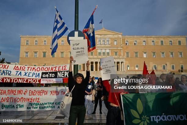 People hold banners and placards, with one reading 'no to privatisations, hands down from water' during a demonstration against Greek Governments...