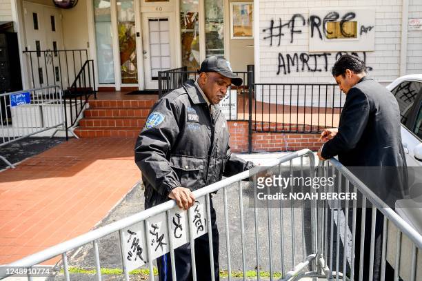 Security guard adjusts barricades at the Indian Consulate as broken windows and a graffitti reading "FreeAmritpal" are seen behind, in San Francisco,...