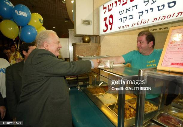 Israel's Shinui party leader Tommy Lapid shakes hands with a supporter 26 January 2003, during a visit to a Jerusalem mall as part of his election...