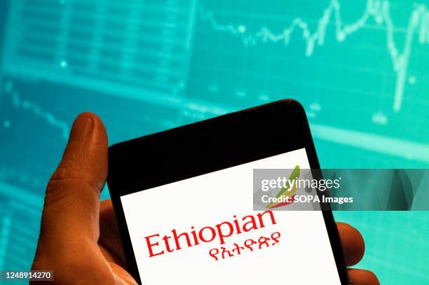 In this photo illustration, the national airline of Ethiopia Ethiopian Airlines logo seen displayed on a smartphone with an economic stock exchange...