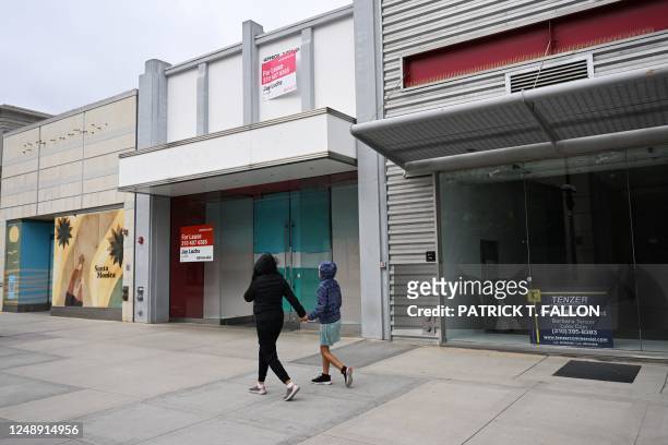 Pedestrians walk past vacant retail store fronts for lease along the Third Street Promenade in Santa Monica, California on March 20, 2023.