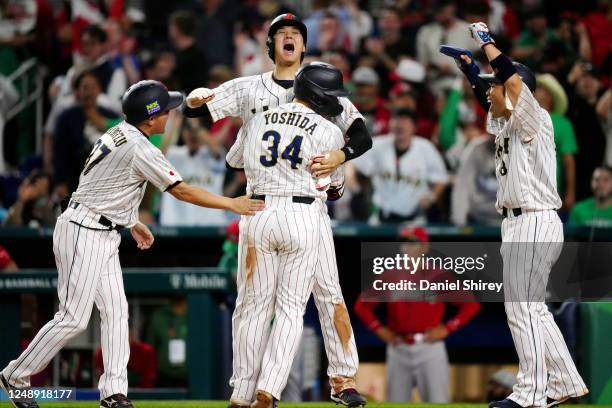 Masataka Yoshida of Team Japan is greeted at home plate by teammate Shohei Ohtani after hitting a three-run home run in the eighth inning during the...