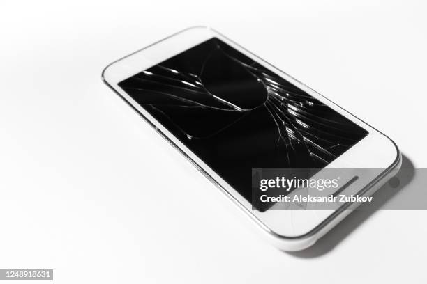 a white mobile phone is broken screen on white background.blank for copy space. - broken smartphone fotografías e imágenes de stock