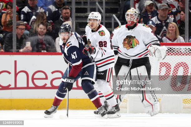 Alex Galchenyuk of he Colorado Avalanche sets up on front of Caleb Jones of the Chicago Blackhawks and Alex Stalock of the Chicago Blackhawks during...