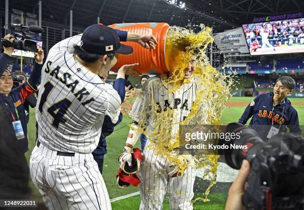 Munetaka Murakami is splashed with a sports drink by teammate Roki Sasaki after hitting a walk-off two-run double in the ninth inning of Japan's...