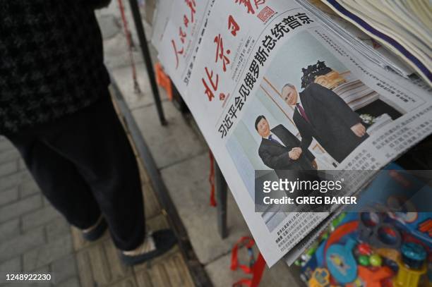 Vendor stands next to newspapers featuring a front page photo of Chinese President Xi Jinping meeting with Russian President Vladimir Putin in...