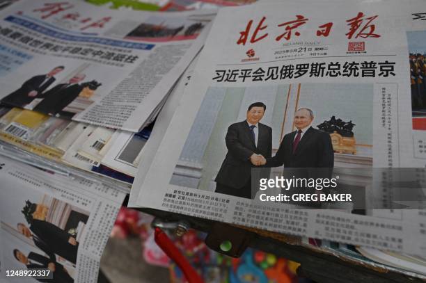Newspapers featuring a front page photo of Chinese President Xi Jinping meeting with Russian President Vladimir Putin in Moscow, are displayed at a...