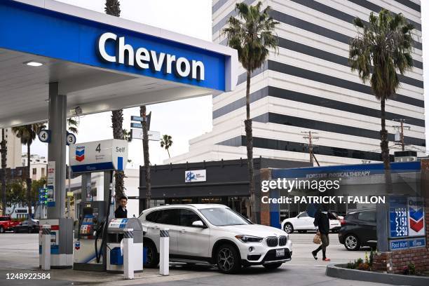 Customer pumps gasoline into a BMW vehicle at a Chevron gas station in Santa Monica, California on March 20, 2023.