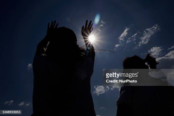 Backlighting of Mexico City residents raising their arms to ''charge themselves with positive energy'' during their visit to the Cerro de la Estrella...