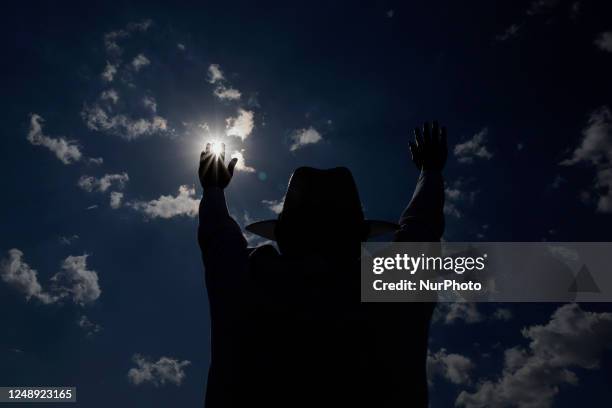 Backlight of a resident of Mexico City raising his arms to ''charge himself with positive energy'' during his visit to the Cerro de la Estrella...