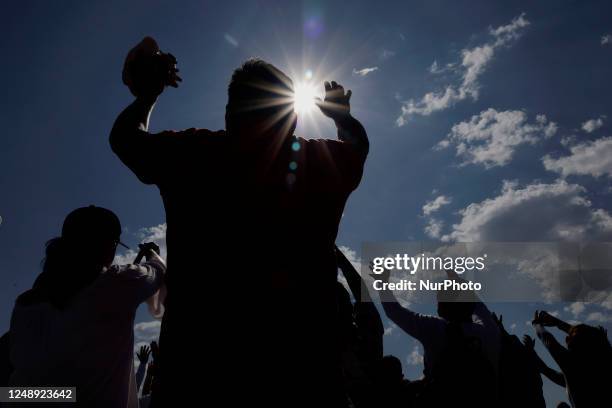 Backlighting of Mexico City residents raising their arms to ''charge themselves with positive energy'' during their visit to the Cerro de la Estrella...