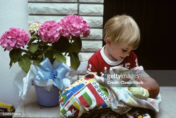 1970s Smiling Blond Boy Holding Looking At His Newborn Baby Sister