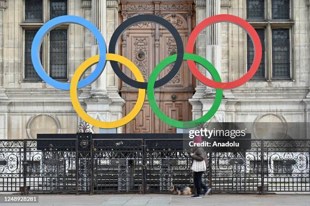 Woman walks past the Olympic Rings on display in front of the Municipality of Paris, France on March 21, 2023.